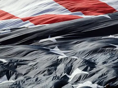 A detailed close-up of the American flag gracefully waving in the wind, showcasing its textures.